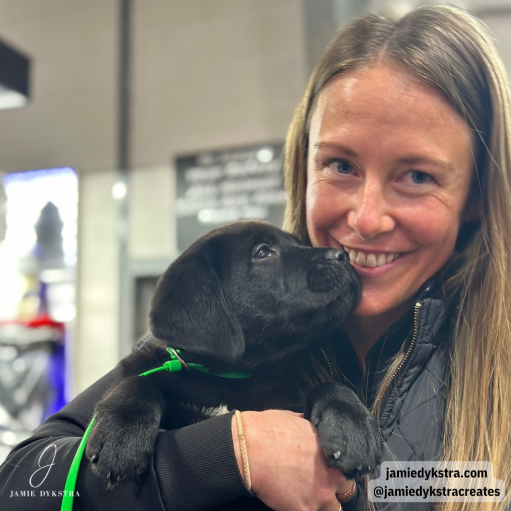 A picture of me holding a black lab puppy with him looking at me.