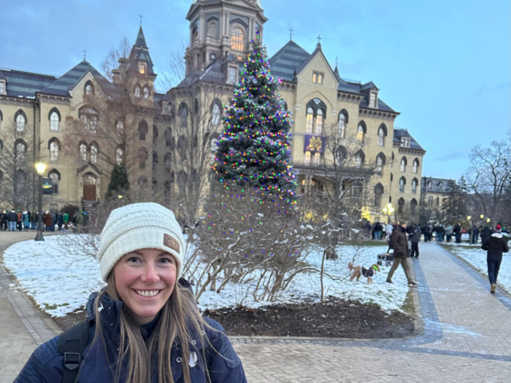 A picture of me standing in front of the Golden Dome at Notre Dame with a Christmas tree in the background.
