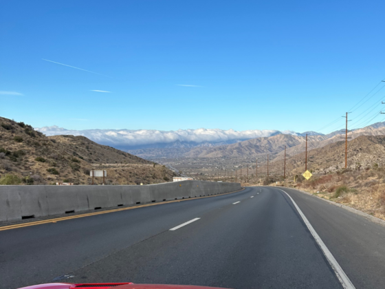 A picture on a highway coming down a mountain highway to a plume of clouds.