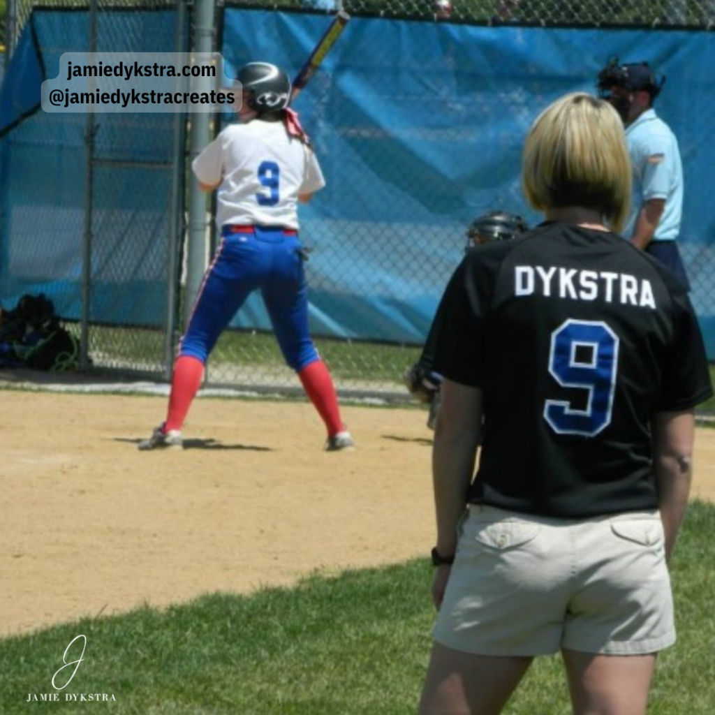 A picture of me in a black softball jersey coaching on the third base line.