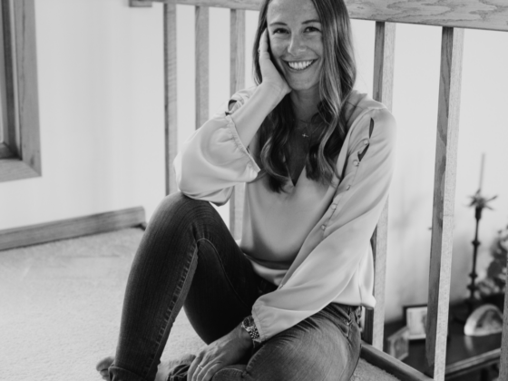 A black and white picture of me sitting on the floor leaning again spires of a railing.