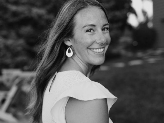 A black and white photo of me looking back over my shoulder in a short sleeve sundress.