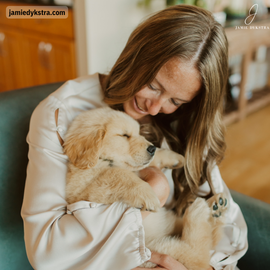 A photo of me sitting in a teal armchair holding a golden retriever puppy.