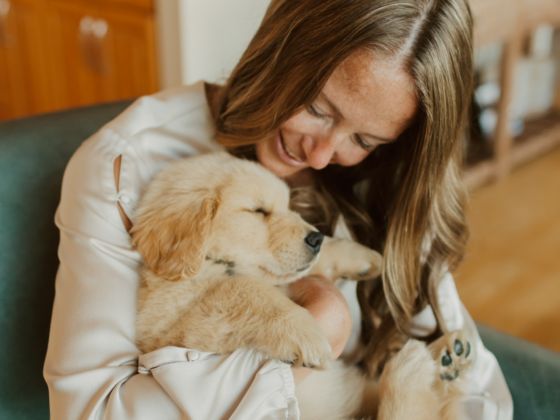 A photo of me sitting in a teal armchair holding a golden retriever puppy.