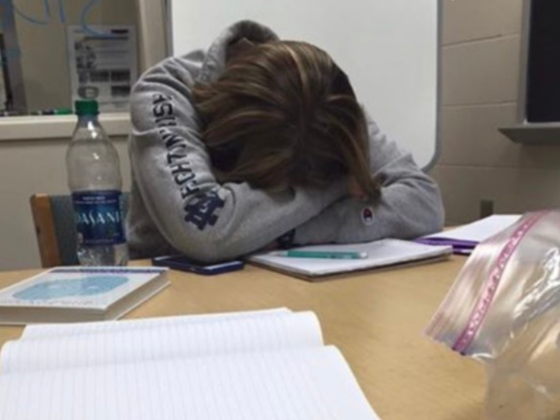 A photo of me with my head down in my arms on a table with books and notebooks in front of me.