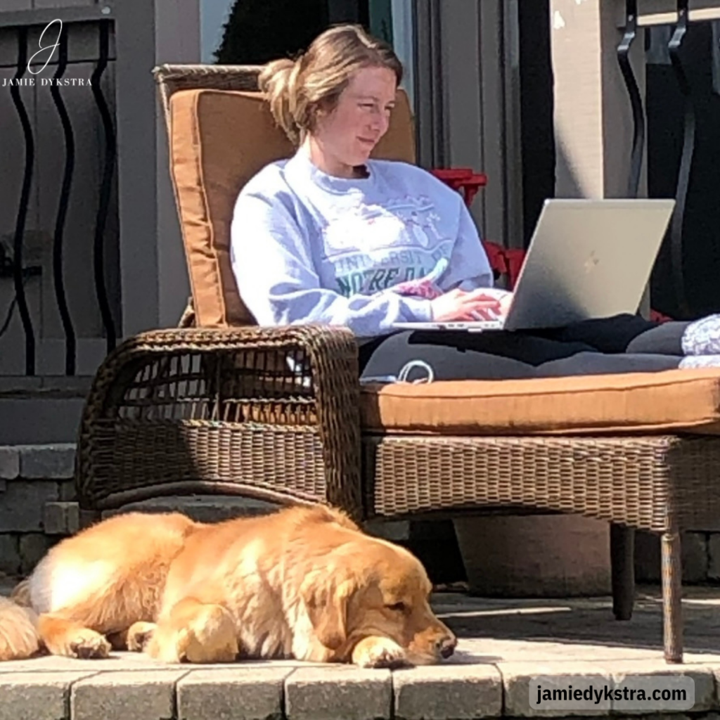 A photo of me in a lounge chair with my laptop and golden retriever laying next to me. I'm wearing a gray sweatshirt and black leggings.
