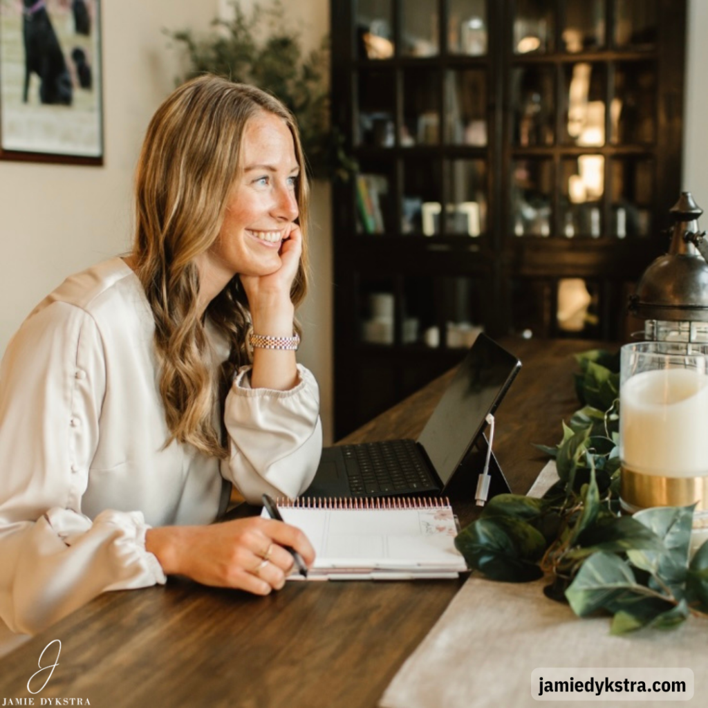 A picture of me sitting at a table facing the right side of the photo with a notebook and pen in hand.