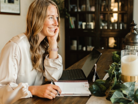 A picture of me sitting at a table facing the right side of the photo with a notebook and pen in hand.
