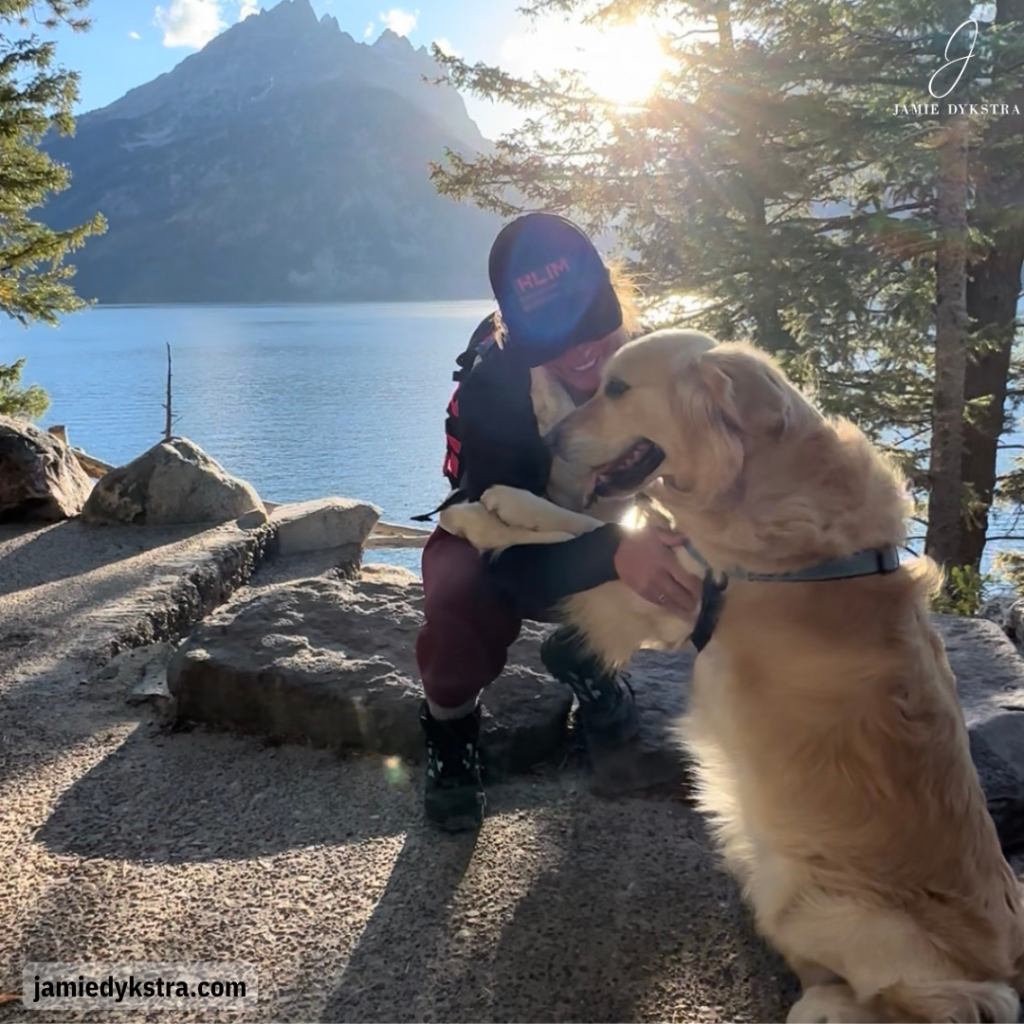 A photo of me hugging a golden retriever in front of a lake and a mountain.