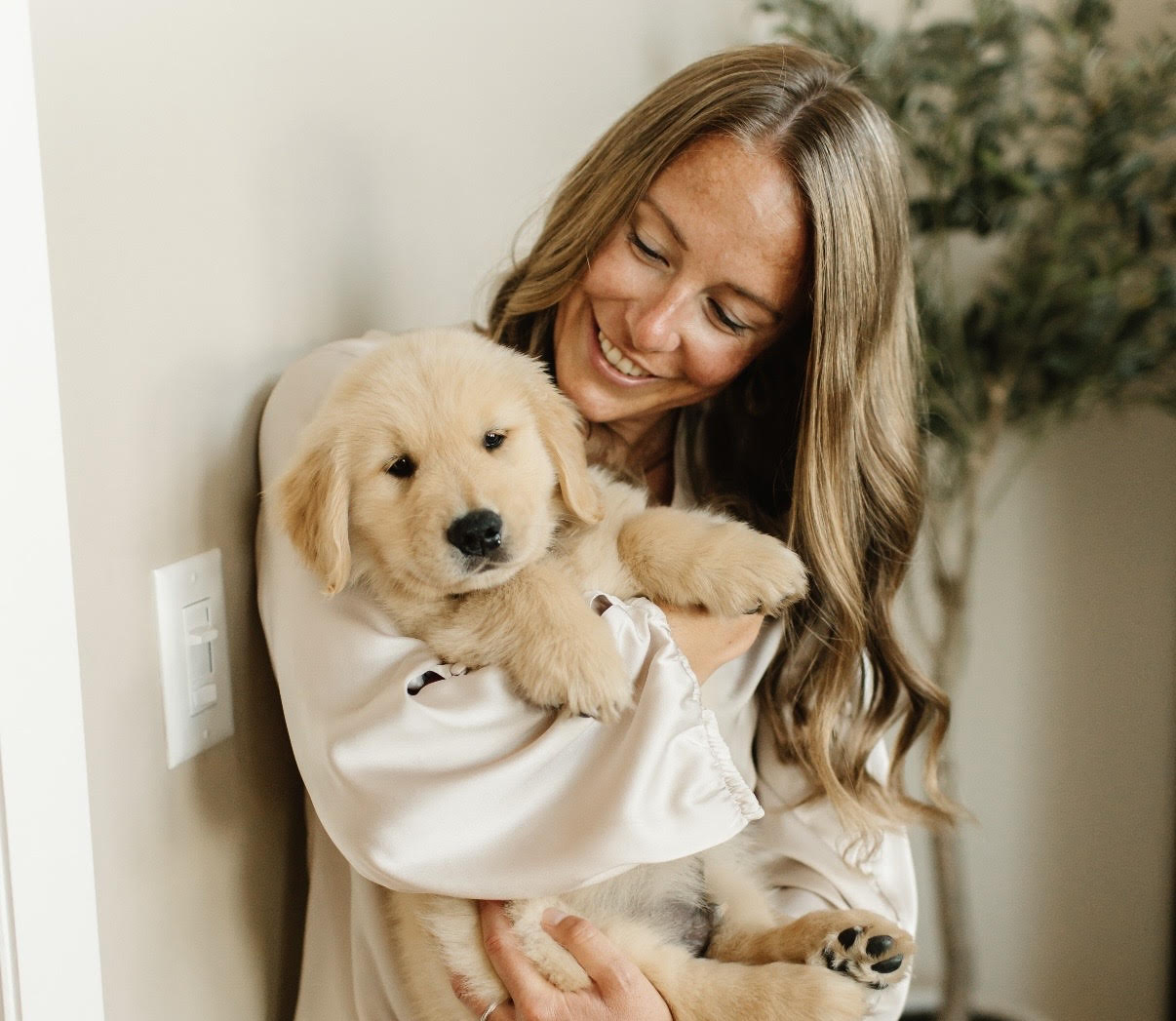 A photo of me holding a golden retriever puppy looking at it.