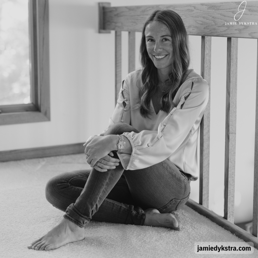 A black and white photo of me sitting against a railing with one leg bent up and my hands resting on my knee.