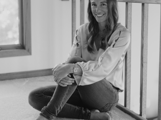 A black and white photo of me sitting against a railing with one leg bent up and my hands resting on my knee.