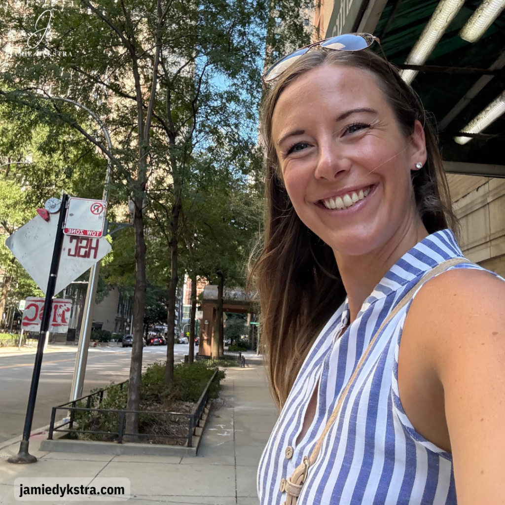 A photo of me taking a selfie on a city sidewalk in a blue and white striped dress.